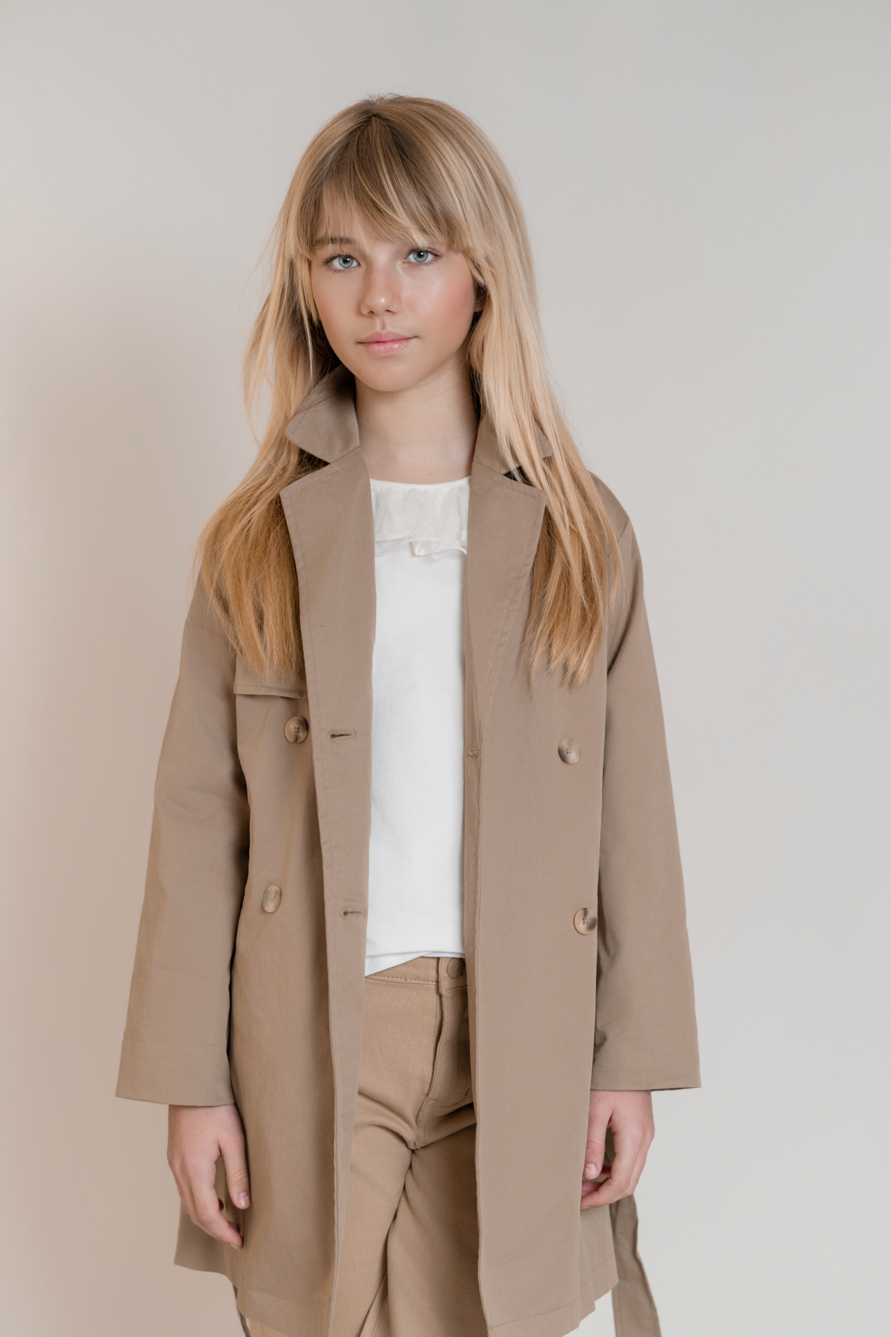 Retrato de modelo infantil con gabardina en tonos neutros